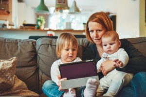 Mother with a baby and a toddler, playing with an Ipad