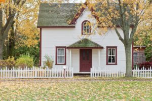 While house with red trim under maple trees