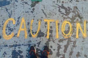 caution written in yellow spray paint on concrete