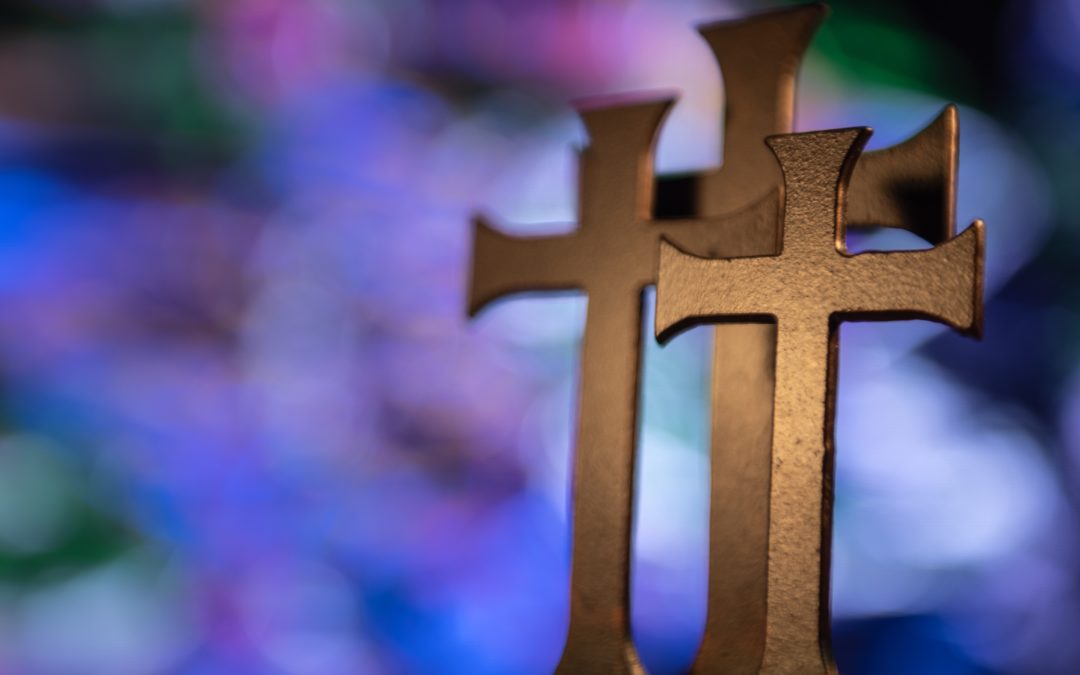 three golden crosses in front of a multicolored background